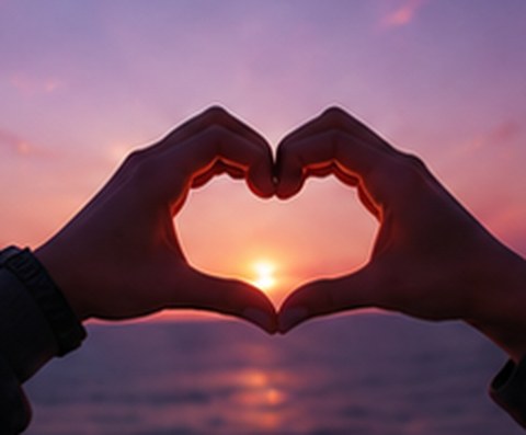 Hands forming a heart around the sunset